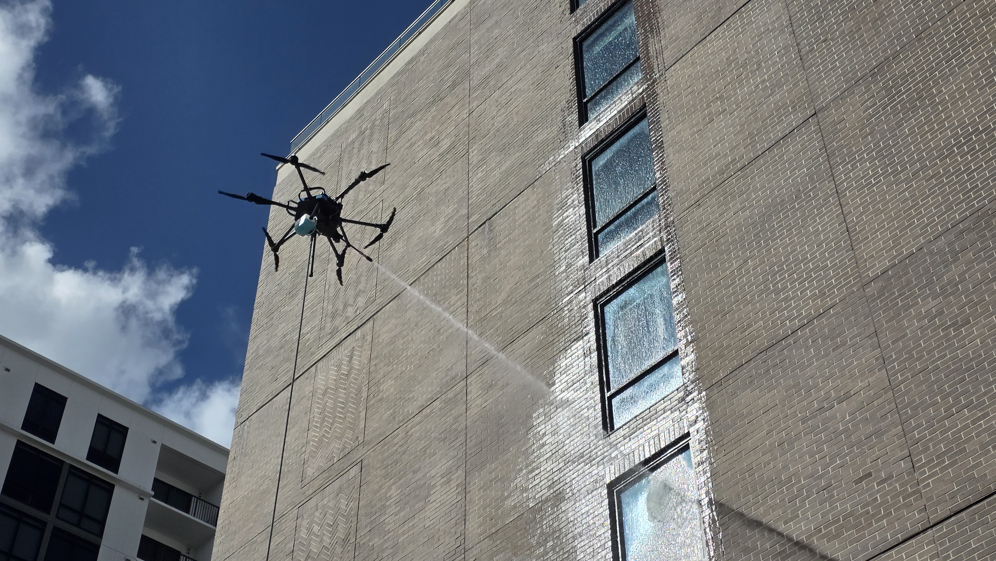 Aerial soft washing on an elevated exterior wall